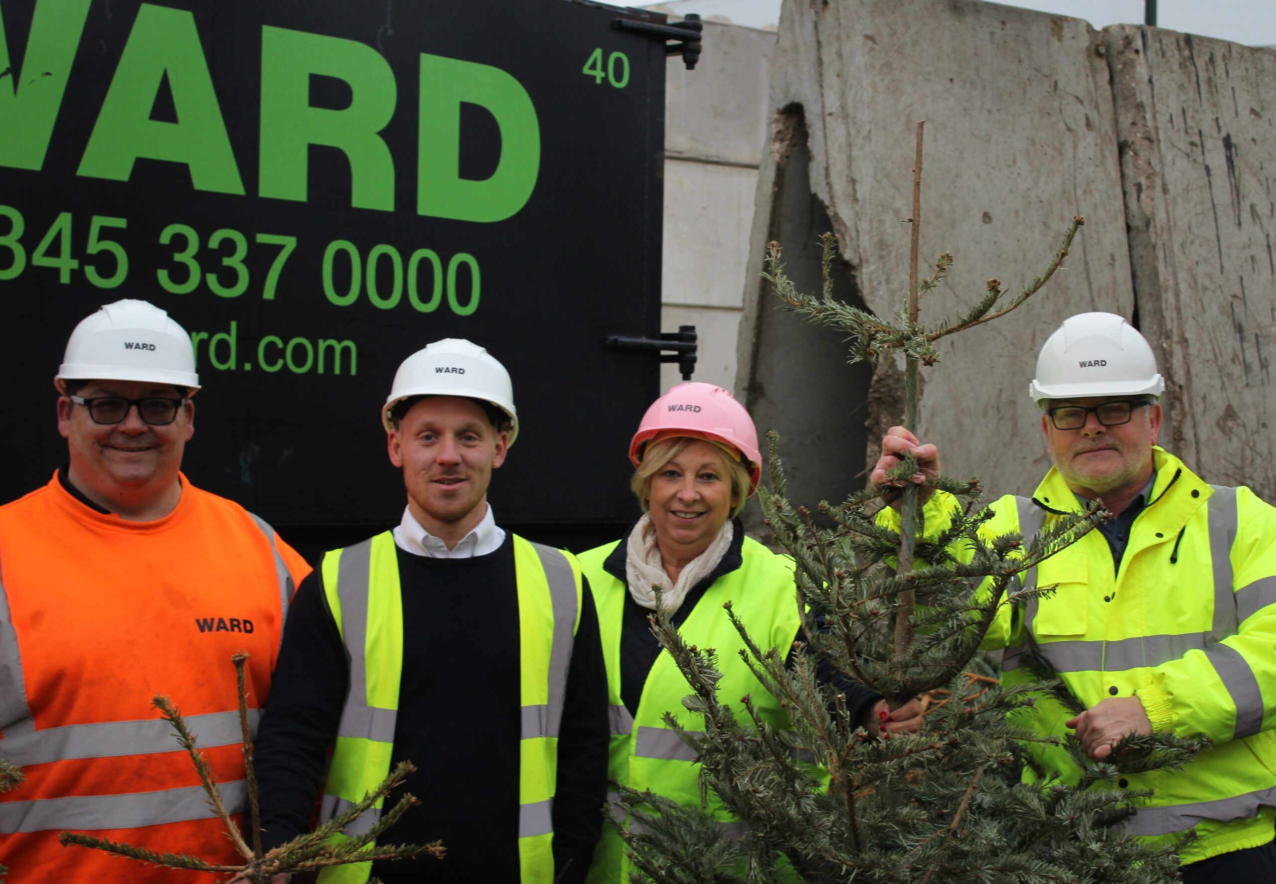 Four people in high vis jackets and hard hats with a collected Christmas tree
